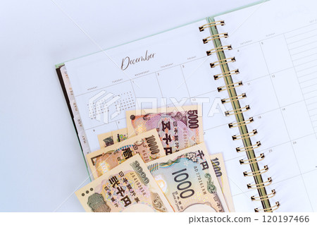 Planner opened to December with various Japanese yen banknotes, including denominations of 1,000, 2,000, 5,000 yen, it is suggests financial planning budgeting. Planner opened to December with various Japanese yen banknotes, including denominations of 1,000, 2,000, 5,000 yen, it is suggests financial planning budgeting. 120197466