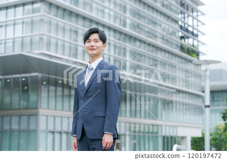 Young businessman smiling in front of an office building 120197472