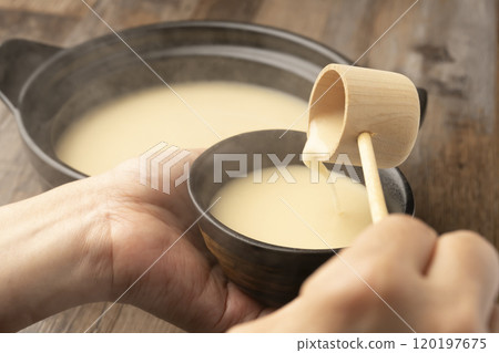 Amazake: Pour warm amazake with a ladle into a teacup held in the hand. 120197675