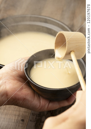 Amazake: Pour warm amazake with a ladle into a teacup held in the hand. 120197678