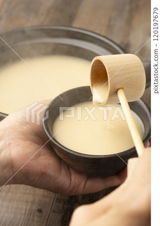 Amazake: Pour warm amazake with a ladle into a teacup held in the hand. 120197679
