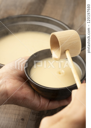 甘酒 用長柄湯匙將溫熱的甘酒倒入手中的茶杯中 甘酒 用長柄湯匙將溫熱的甘酒倒入手中的茶杯中 120197680