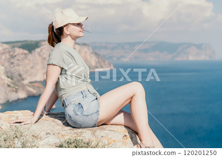 Woman Sitting on a Cliff Overlooking the Ocean Woman Sitting on a Cliff Overlooking the Ocean 120201250