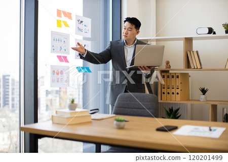 Asian businessman presenting data during video call in modern office Asian businessman presenting data during video call in modern office 120201499