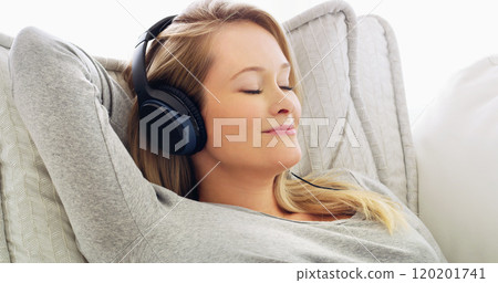 She is in her comfort zone listening to music. Shot of an attractive young woman listening to music with headphones at home. 120201741