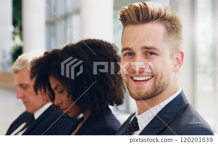 Waiting in line doesnt bother me. Cropped portrait of a handsome young businessman smiling while sitting in a line with his colleagues in the office. Waiting in line doesnt bother me. Cropped portrait of a handsome young businessman smiling while sitting in a line with his colleagues in the office. 120201839