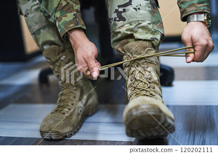 Boots built for battle. Cropped shot of a soldier tying his boot shoelaces in the dorms of a military academy. Boots built for battle. Cropped shot of a soldier tying his boot shoelaces in the dorms of a military academy. 120202111