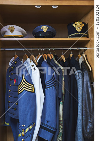 Clothing made for combat. Shot of various military jackets and hats hanging in a closet. 120202124