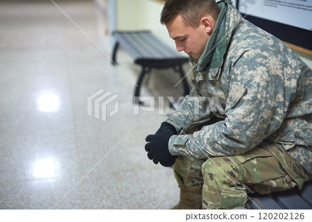 Not every war is fought on a battlefield. Shot of a young soldier sitting on a bench in the hall of a military academy. 120202126