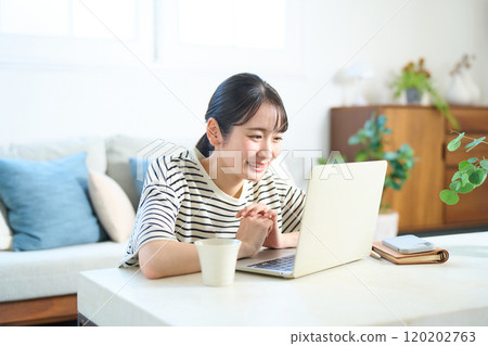 Young woman looking at computer screen, living room, one-room apartment Young woman looking at computer screen, living room, one-room apartment 120202763