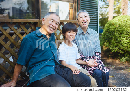 孫子和老夫婦坐在屋外的長椅上 孫子和老夫婦坐在屋外的長椅上 120203182