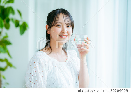 Young woman drinking water in the living room 120204009