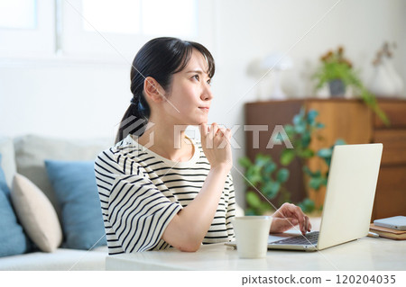 Young woman looking at computer screen, living room, one-room apartment Young woman looking at computer screen, living room, one-room apartment 120204035