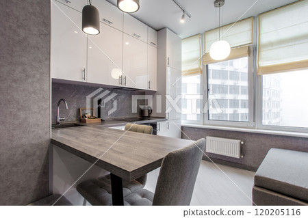 Clean kitchen in a small cozy contemporary studio apartment. Table and chairs in the foreground. Built in household appliance 120205116