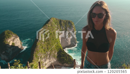 Girl relax on cliff ocean in Indonesia, Nusa Penida Islands Kelingking Secret Point Beach. This captures her bold and adventurous spirit amidst the stunning coastal landscape. Girl relax on cliff ocean in Indonesia, Nusa Penida Islands Kelingking Secret Point Beach. This captures her bold and adventurous spirit amidst the stunning coastal landscape. 120205565