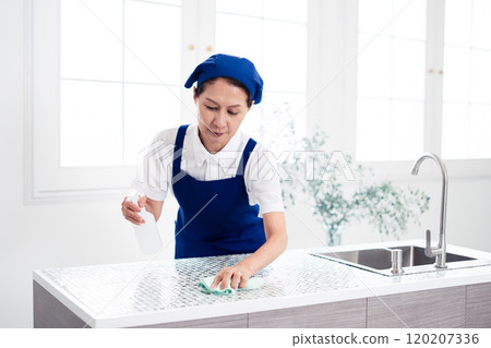 Senior female housekeeper cleaning the kitchen 120207336