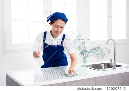 Senior female housekeeper cleaning the kitchen Senior female housekeeper cleaning the kitchen 120207342