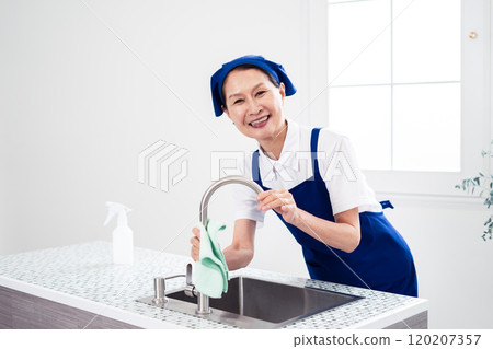 Senior female housekeeper cleaning the kitchen Senior female housekeeper cleaning the kitchen 120207357