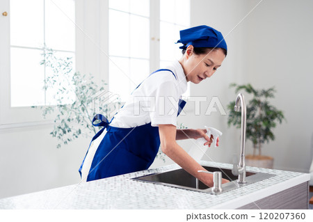 Senior female housekeeper cleaning the kitchen Senior female housekeeper cleaning the kitchen 120207360