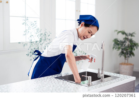 Senior female housekeeper cleaning the kitchen Senior female housekeeper cleaning the kitchen 120207361
