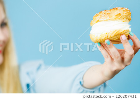 woman holds cream puff cake in hand 120207431