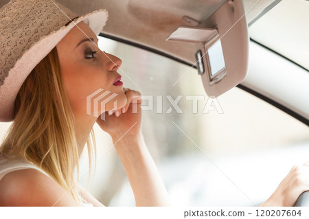 Distracted woman driving her car looking in mirror Distracted woman driving her car looking in mirror 120207604