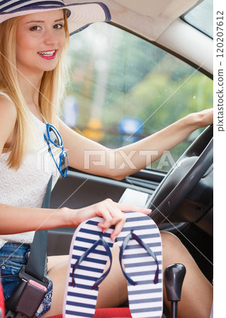 Pretty woman sit in car holds flip flops in hand Pretty woman sit in car holds flip flops in hand 120207612