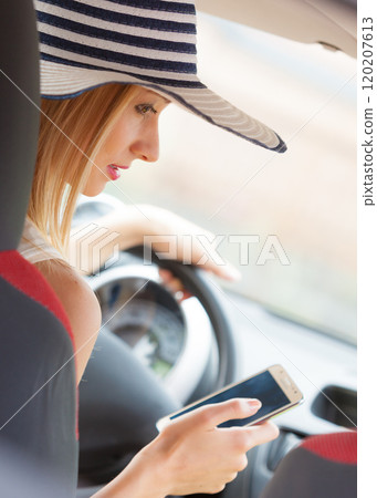 Woman using phone while driving her car Woman using phone while driving her car 120207613