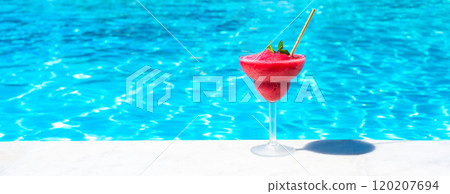 Chilled red drink on pool edge in bright sunlight. Concept of tropical refreshment and summer leisure 120207694