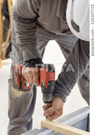 Carpenter working on wooden board using professional electric cordless screwdriver 120207728