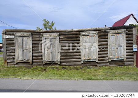 The walls of an old wooden house used as a fence in Barabinsk, Russia. Inscription: Trudovoy Lane The walls of an old wooden house used as a fence in Barabinsk, Russia. Inscription: Trudovoy Lane 120207744