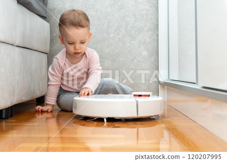 Little girl holds robot vacuum cleaner with her hand. Concept of communication with smart devices 120207995