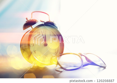 Background with a clock on the table and bokeh in pastel rainbow colors. Time for rest and travel. 120208887