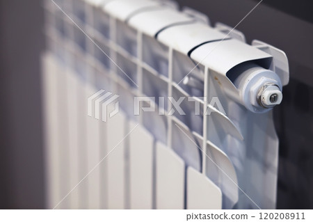 White modern aluminum radiator battery for hot water heating, on the background of a wall in the interior of an apartment or office space. 120208911