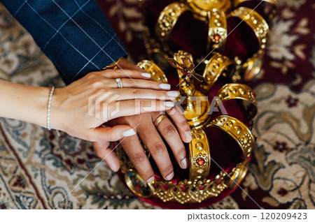 two wedding crowns in the church. The hands of the newlyweds lie on the crown two wedding crowns in the church. The hands of the newlyweds lie on the crown 120209423