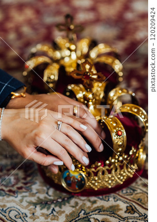 two wedding crowns in the church. The hands of the newlyweds lie on the crown two wedding crowns in the church. The hands of the newlyweds lie on the crown 120209424