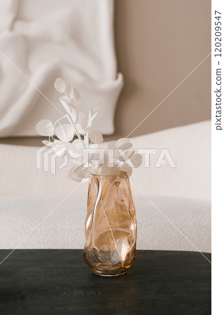 Glass unique vase with white flowers in it on a table at modern living room 120209547