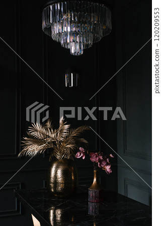 Gold vase with a flower in it sits on a black table 120209553