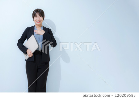 A refreshing, young, conscientious woman in a business image wearing a suit and holding a laptop computer, looking at the camera A refreshing, young, conscientious woman in a business image wearing a suit and holding a laptop computer, looking at the camera 120209583