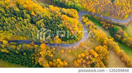 A winding road meanders through a colorful landscape adorned with vibrant autumn foliage, showcasing shades of yellow, orange, and red as leaves transition with the season. A winding road meanders through a colorful landscape adorned with vibrant autumn foliage, showcasing shades of yellow, orange, and red as leaves transition with the season. 120209848
