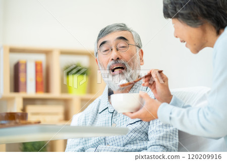 Senior woman feeding her husband 120209916
