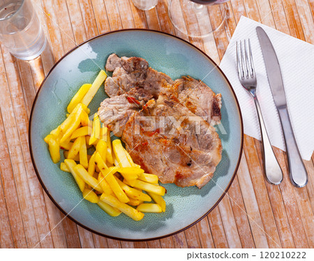 Baked pork chops on bone served with french fries Baked pork chops on bone served with french fries 120210222