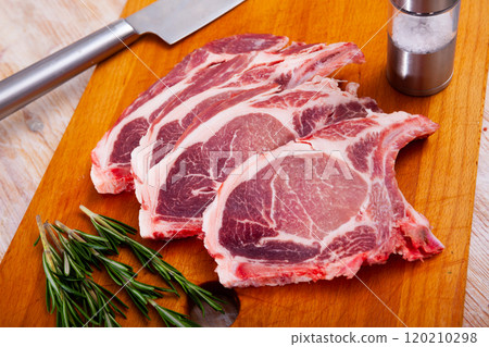 Raw pork's chops and rosemary on wooden surface Raw pork's chops and rosemary on wooden surface 120210298