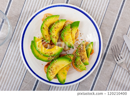 On plate are sandwiches with bran bread and avocado, sprinkled with sesame seeds On plate are sandwiches with bran bread and avocado, sprinkled with sesame seeds 120210400