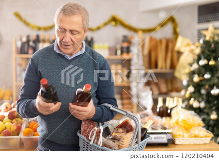 Mature female customer choosing whiskey for Christmas celebration at supermarket 120210404