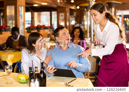 Man and woman talking about menu with waitress in restaurant 120210405