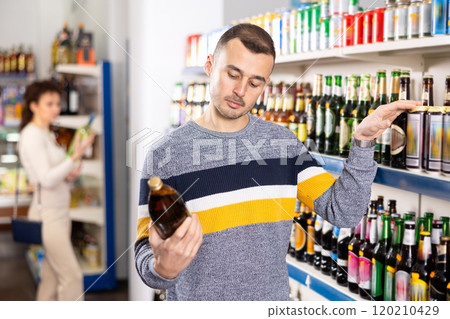 In Russian goods store, man choose bottle of beer In Russian goods store, man choose bottle of beer 120210429