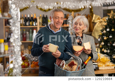 Elderly couple is looking at cheese in store on eve of New Year holidays 120210664
