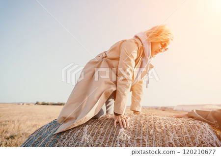 Woman in Trench Coat Leaning on Hay Bale 120210677