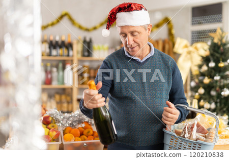 Happy mature man buying bottles of wine at grocery supermarket to celebrate Christmas 120210838